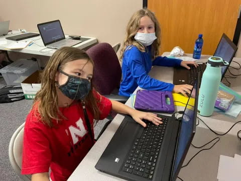 a couple of girls using laptops