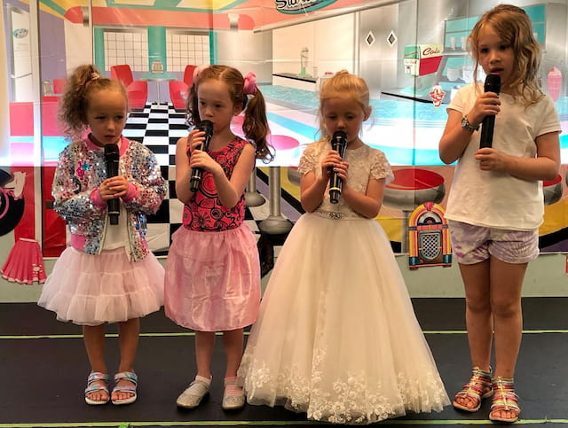 a group of girls singing on stage