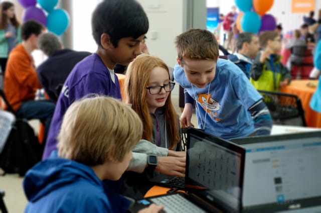a group of children looking at a laptop