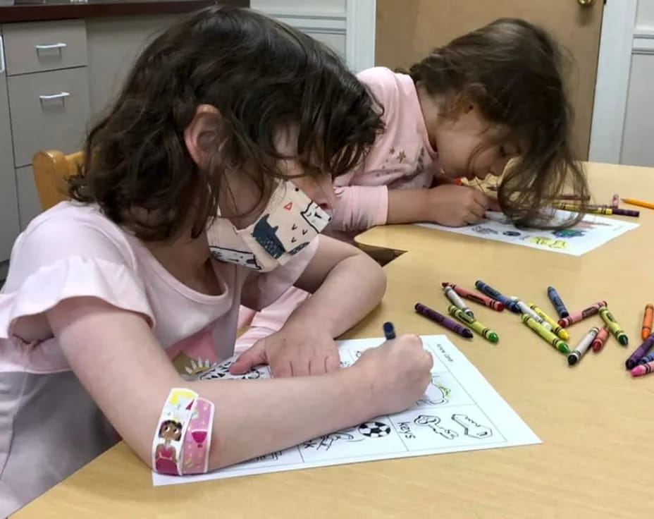 a few young girls coloring on paper