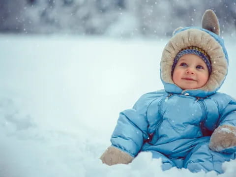a baby in a blue coat in the snow
