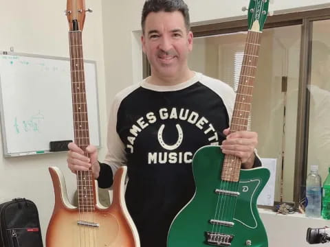 a man holding a couple of guitars