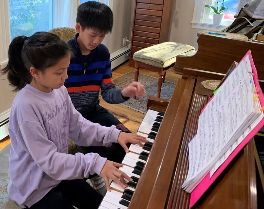 a boy and girl playing piano