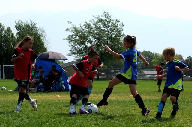 a group of kids compete over a football ball