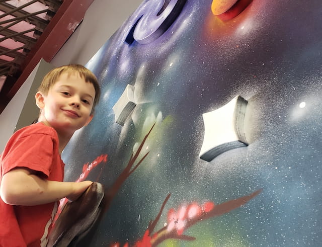 a boy standing next to a large blue ball