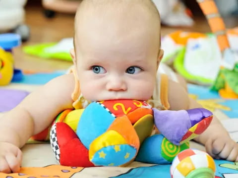 a baby lying on a colorful blanket