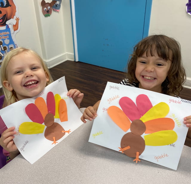a couple of children holding up drawings