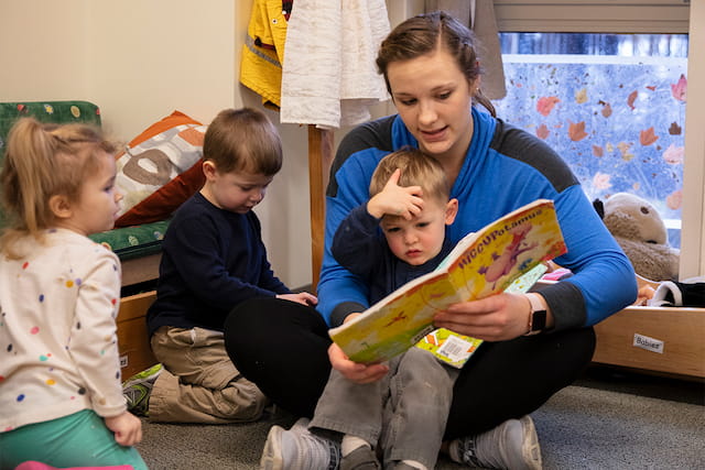 a person reading a book to a couple of children