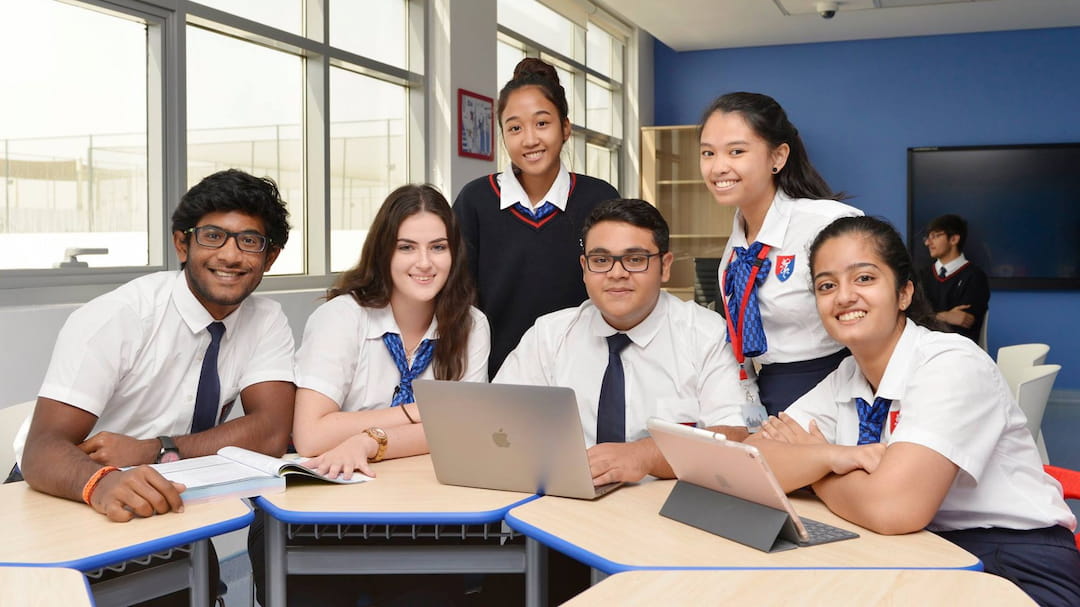 a group of people sitting at a table with laptops