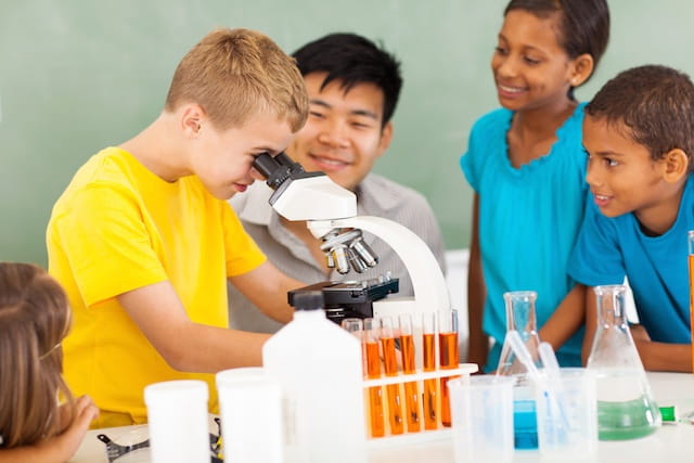 a group of kids looking at a microscope