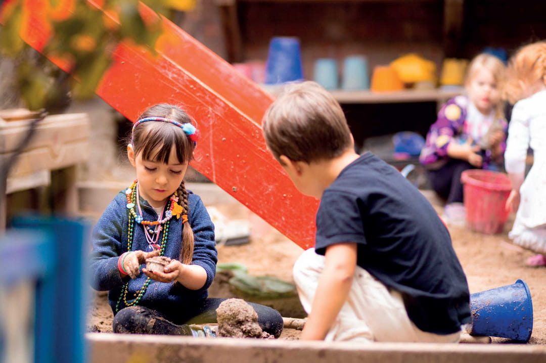 a boy and girl playing with sand