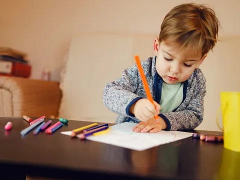 a young boy coloring on a paper