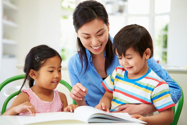a person and two children looking at a book