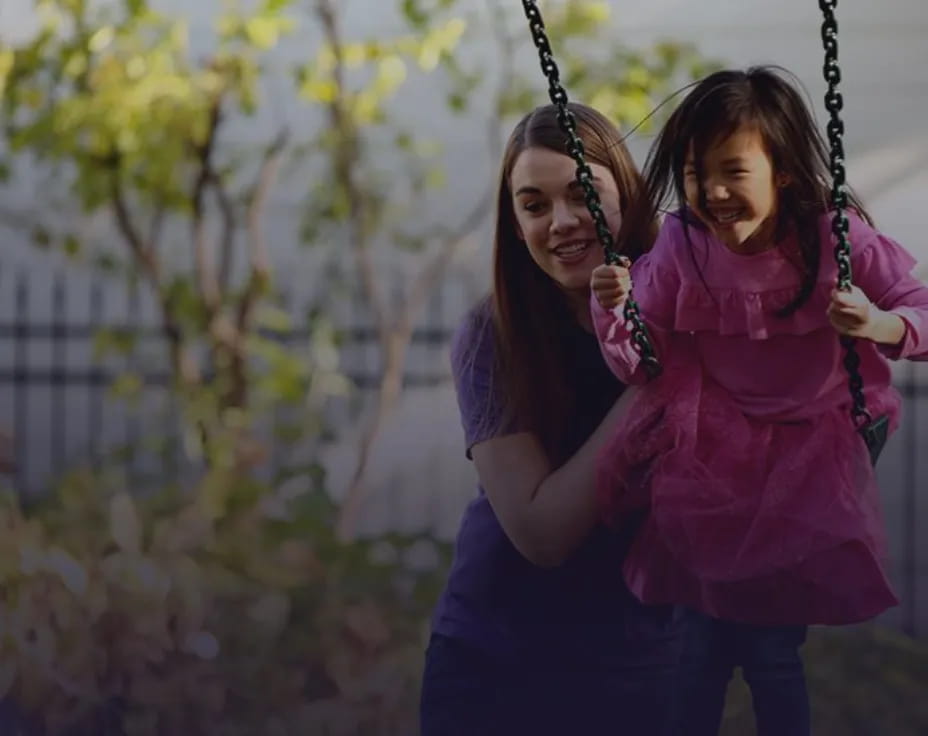 a person holding a girl on a swing