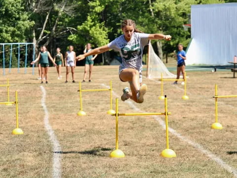 a girl jumping over yellow poles