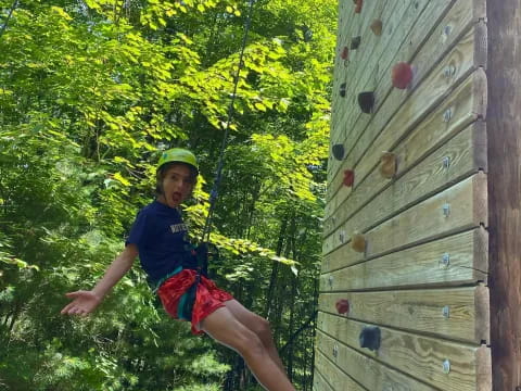 a boy climbing a wooden fence