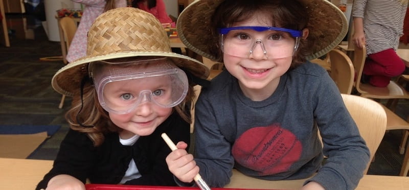 a couple of girls wearing hats and sitting at a table