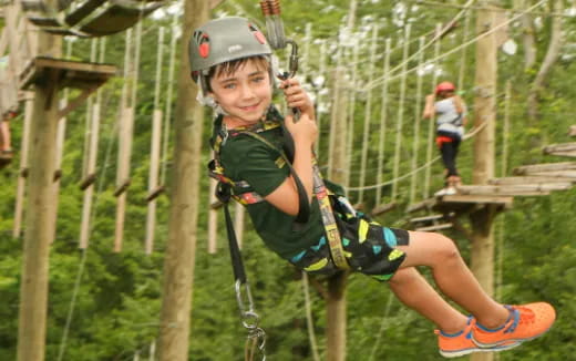 a boy wearing a helmet and climbing a rope