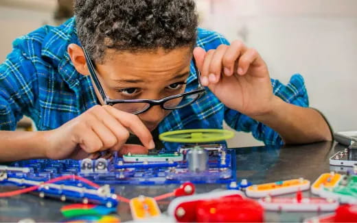 a boy with glasses looking at a board game