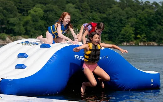 a couple of girls on a floating raft in a lake