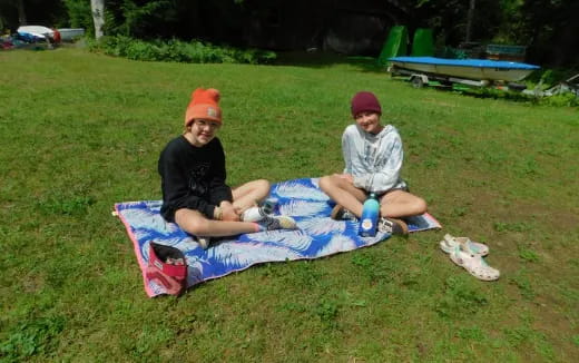 a couple of people sitting on a blanket on the grass