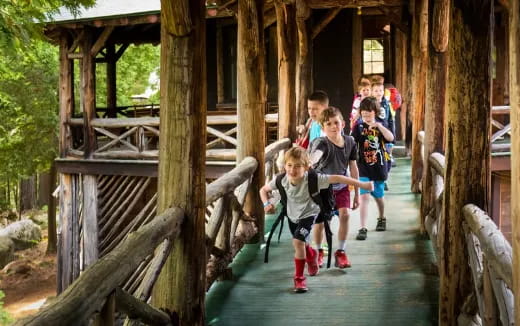 a group of kids playing on a wooden bridge