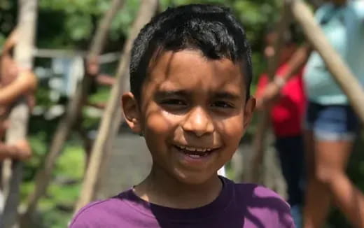 a boy smiling with a group of people behind him