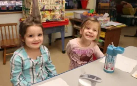a couple of girls sitting at a table
