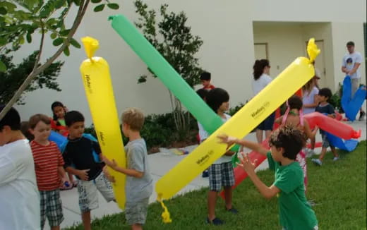 a group of kids playing with a yellow and green toy
