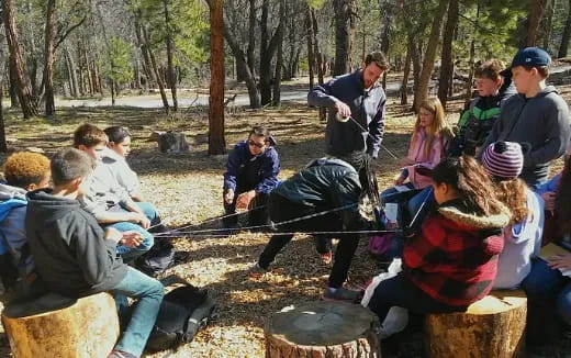 a group of people sitting on a bench in a forest