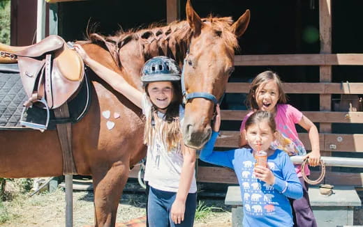 a group of children stand near a horse