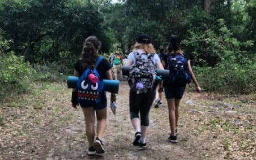 a group of people walking on a dirt path in the woods