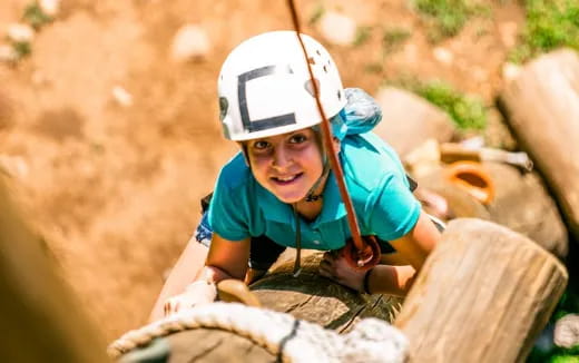a young boy wearing a helmet and climbing a tree