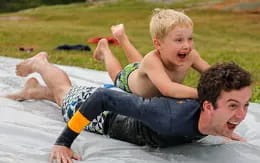 a person and a boy on a blanket in the grass