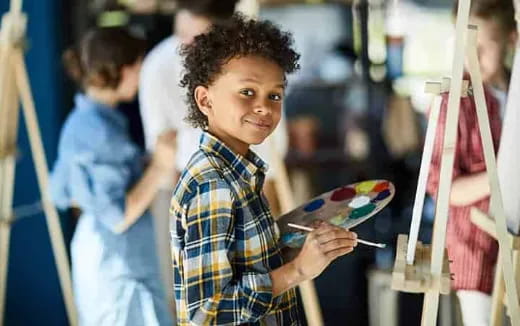 a young boy holding a paintbrush