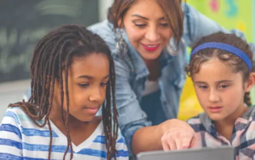 a person and a few children looking at a laptop
