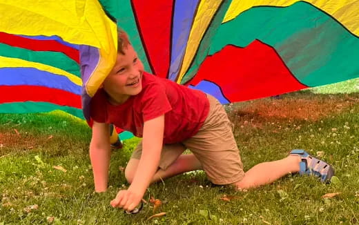 a boy sitting under a colorful umbrella