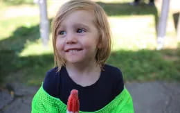 a girl smiling and holding a red object