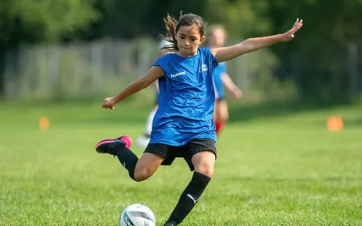 a girl kicking a football ball