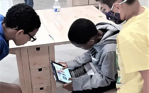 a group of people looking at a laptop