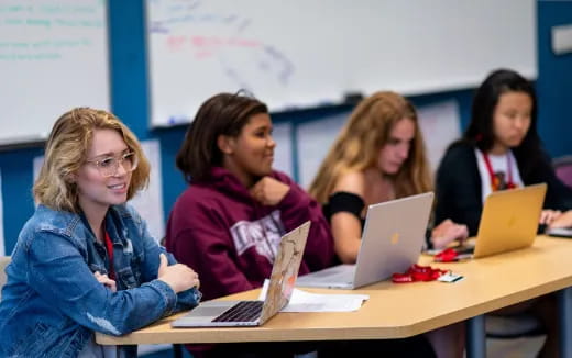 a group of women sitting at a table with laptops