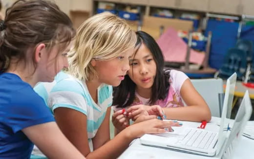 a group of young girls looking at a computer screen