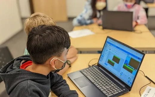 a couple of boys looking at a laptop