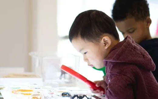 a couple of kids looking at a red pen