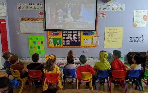 a group of children sitting in chairs in a classroom