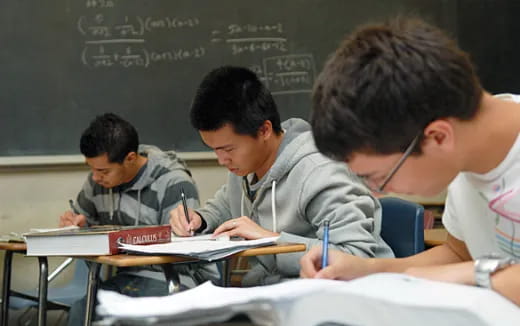 a group of men sitting at desks writing on paper