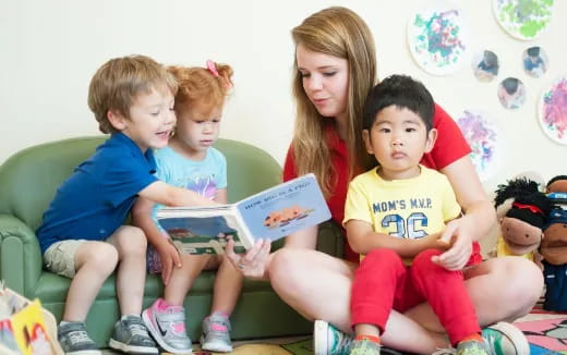 a person reading a book to a group of children