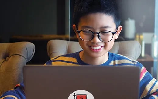 a boy wearing glasses and looking at a laptop