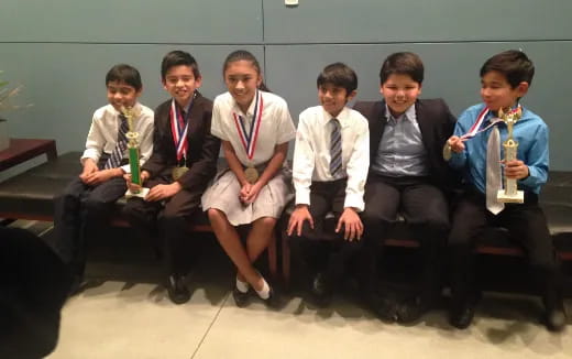 a group of people sitting on a bench holding trophies