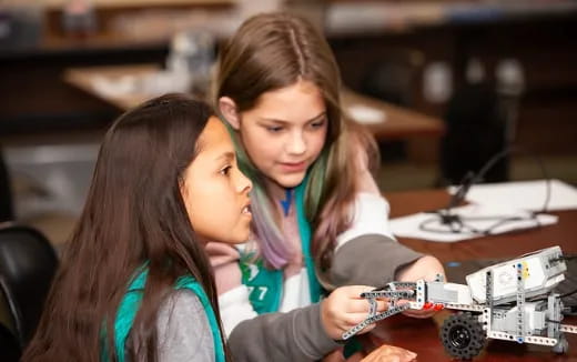a few young girls looking at a toy car